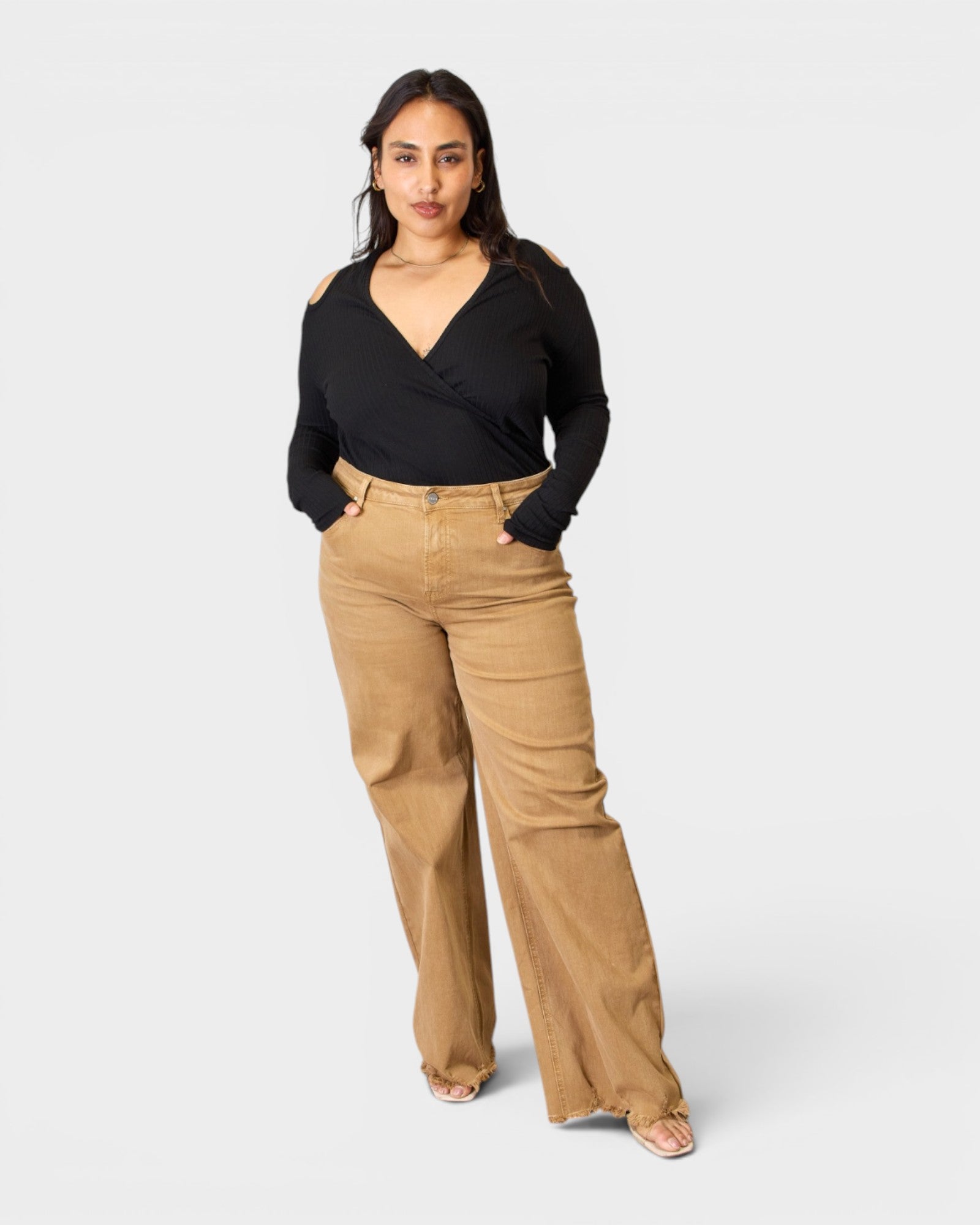 Woman wearing a black top and tan pants on a white background