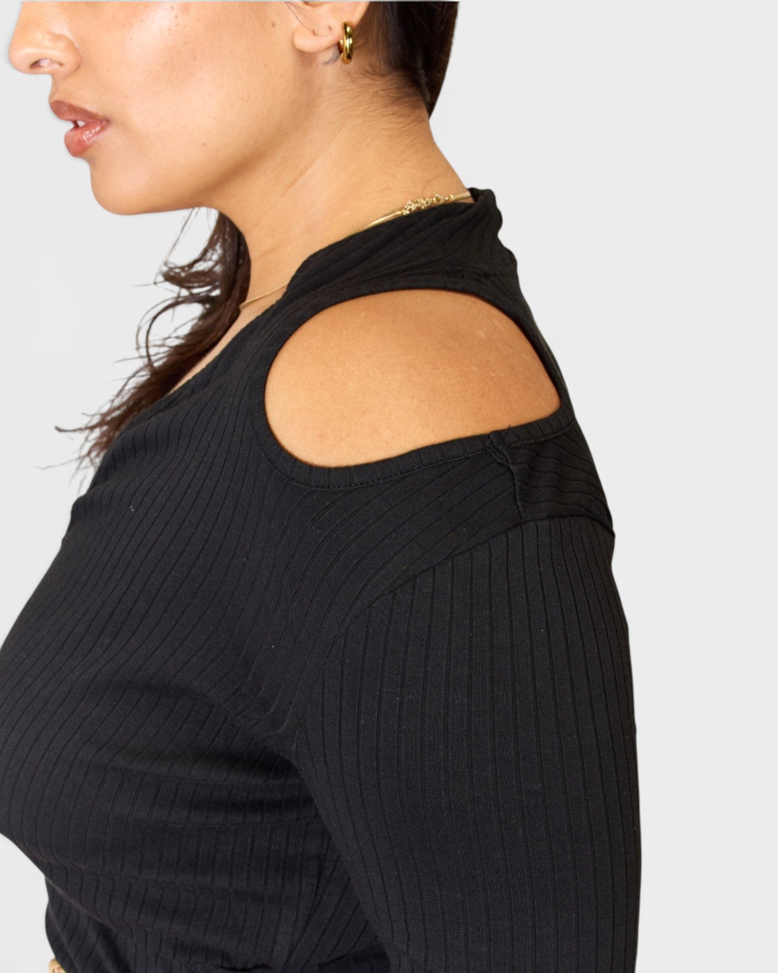 Black ribbed sweater with cut-out shoulder detail on a plain background