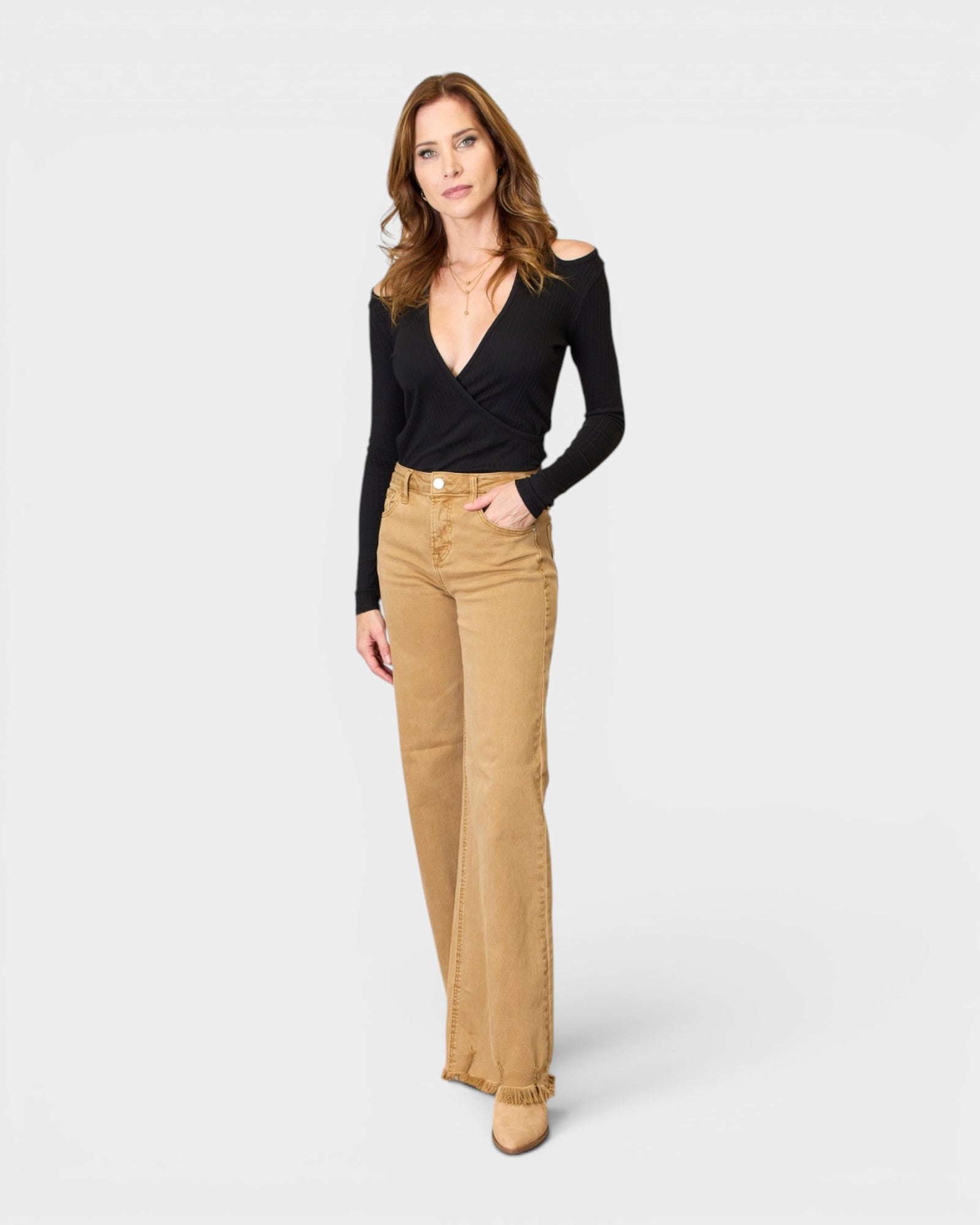 Woman wearing a black top and beige pants on a white background