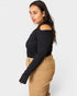 Woman wearing a black top and beige pants on a white background
