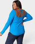Woman wearing a blue long-sleeve top with open back design on a white background