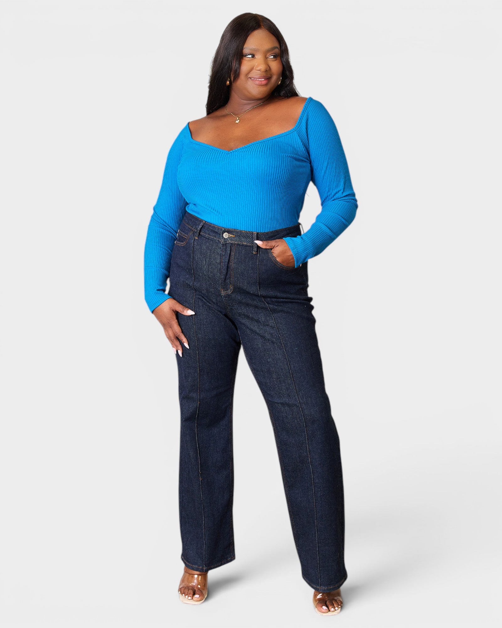 Woman wearing a blue top and dark jeans on a white background