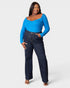 Woman wearing a blue top and dark jeans on a white background