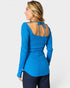 Woman wearing a blue ribbed long-sleeve top with open back on a white background