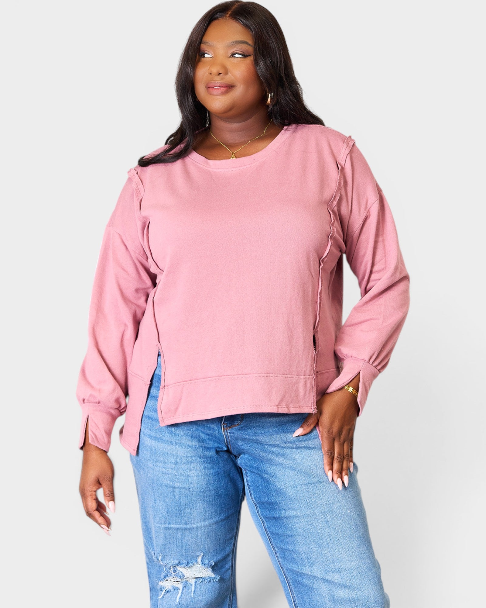 Woman wearing a pink sweatshirt and blue jeans on a white background