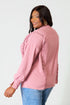 Woman wearing a pink jacket and blue jeans on a white background