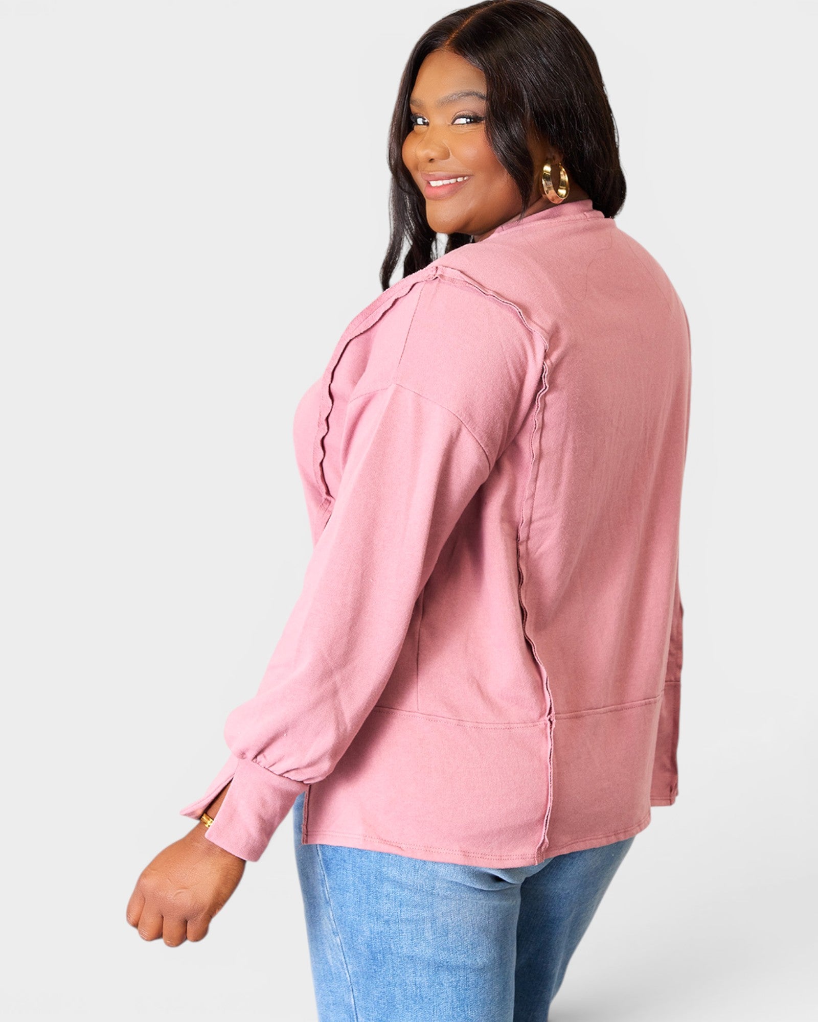 Woman wearing a pink jacket and blue jeans on a white background