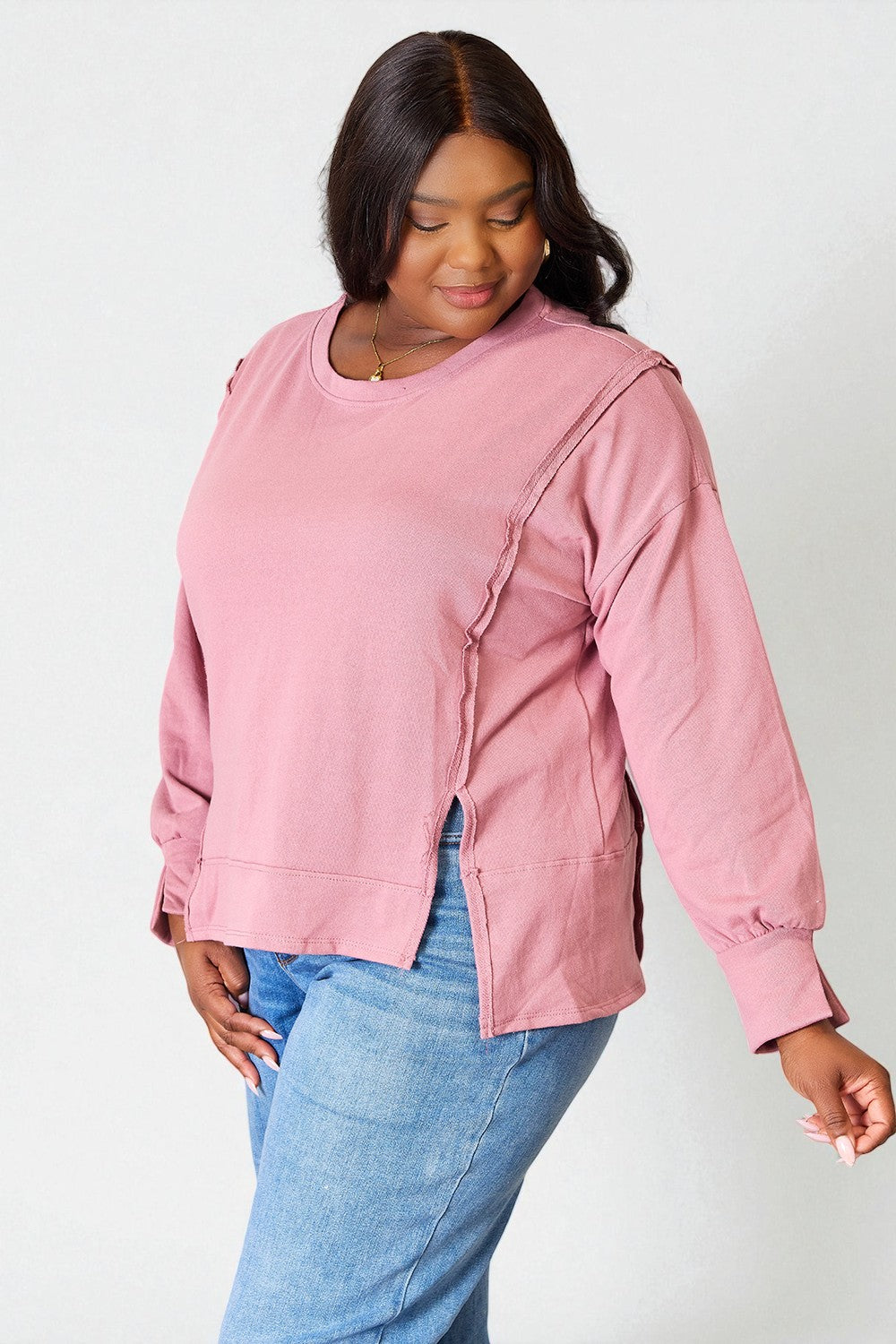 Person wearing a pink sweatshirt and blue jeans on a white background