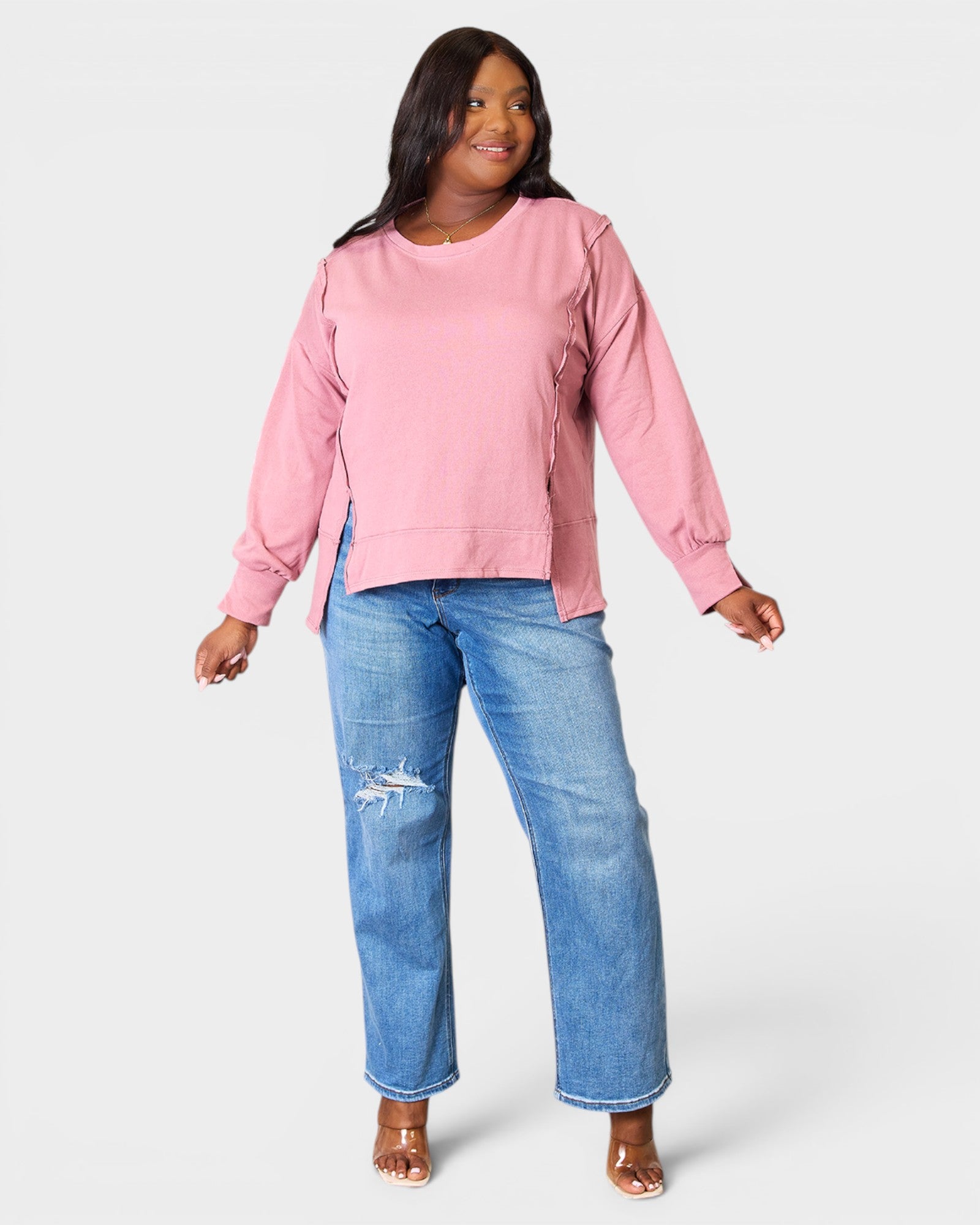 Woman wearing a pink top and blue jeans on a white background