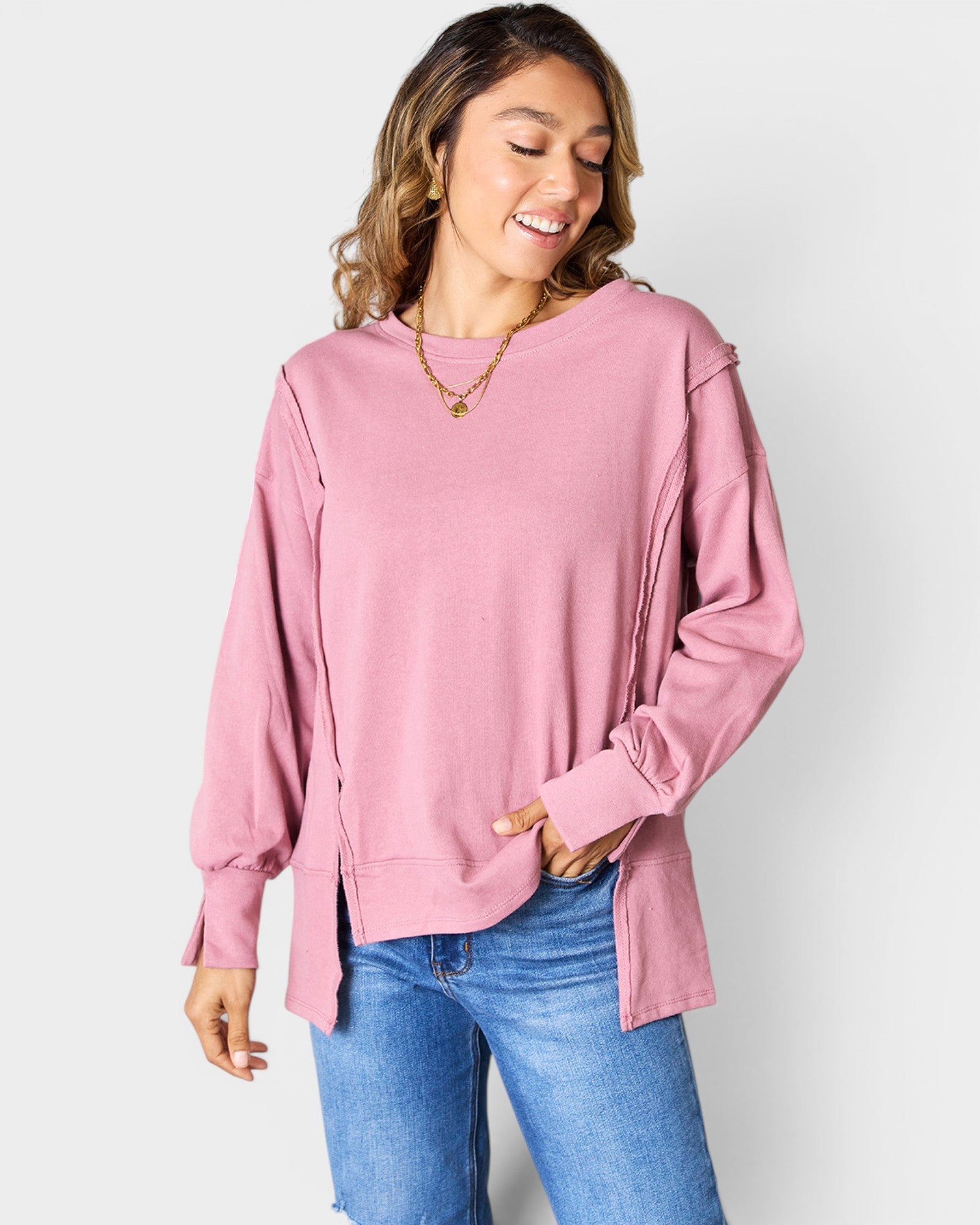 Woman wearing a pink sweatshirt and blue jeans on a white background
