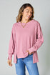 Woman wearing a pink oversized sweater and blue jeans against a plain background