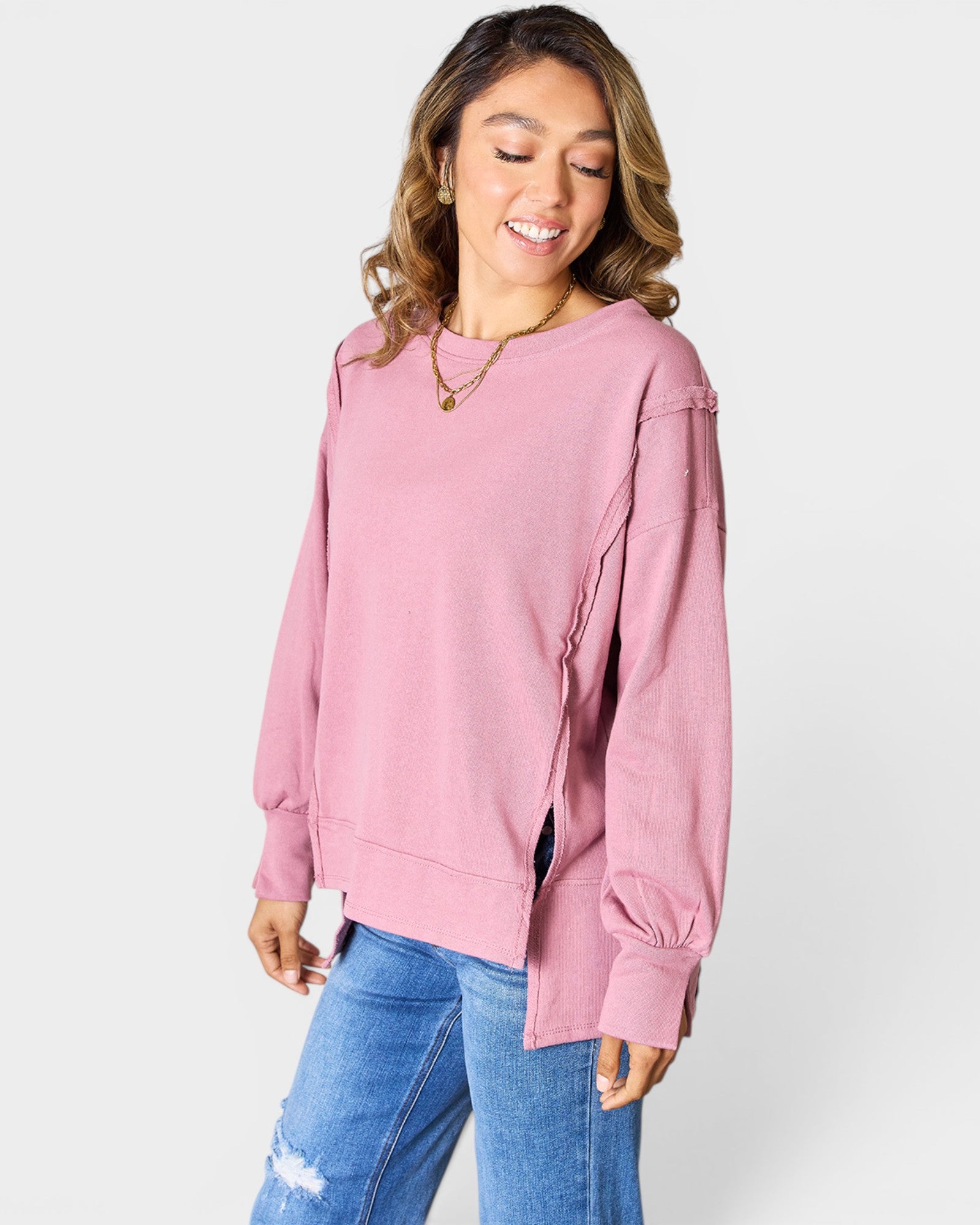 Woman wearing a pink sweatshirt and blue jeans on a white background