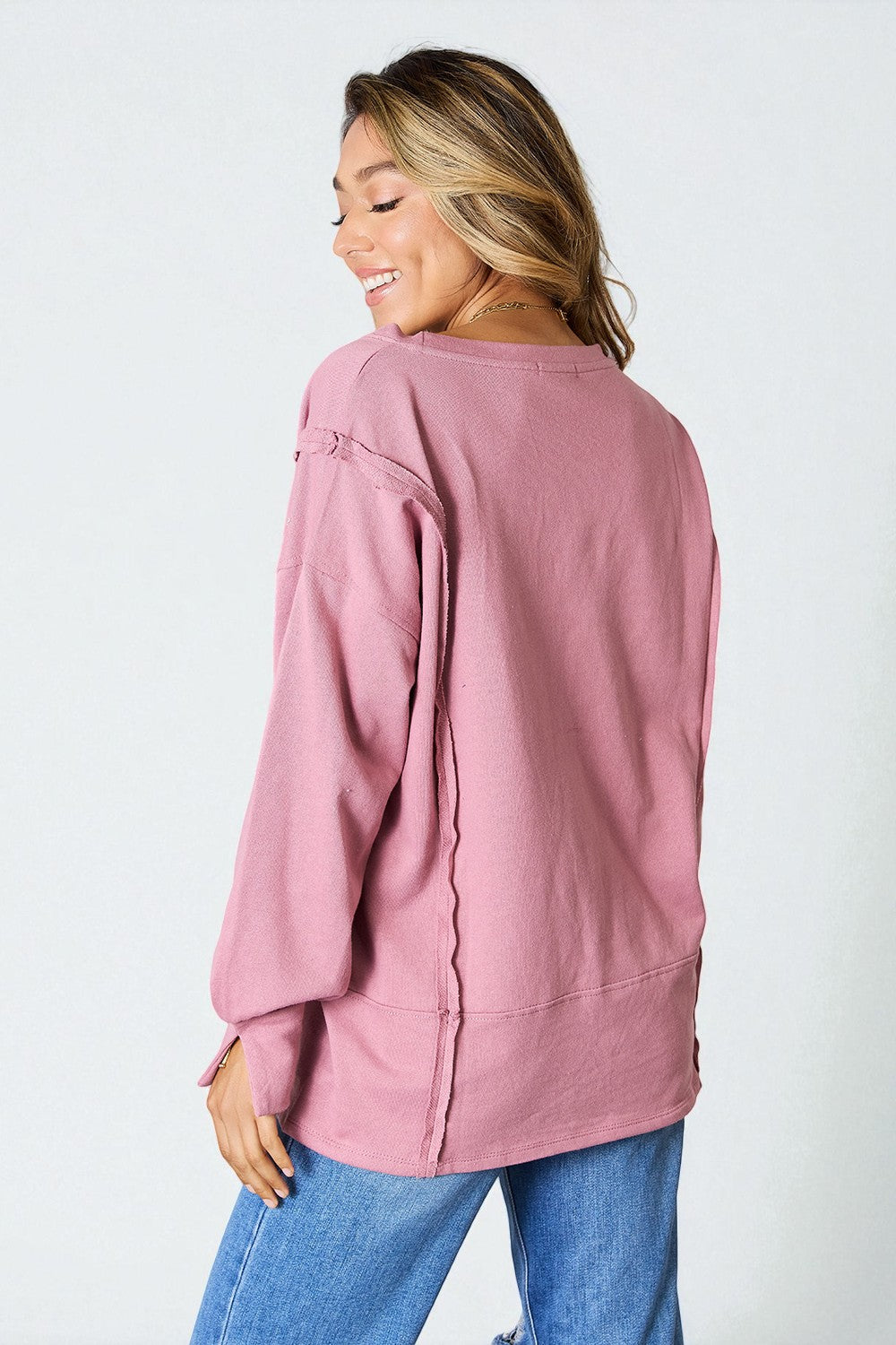 Woman wearing a pink sweater and blue jeans on a white background