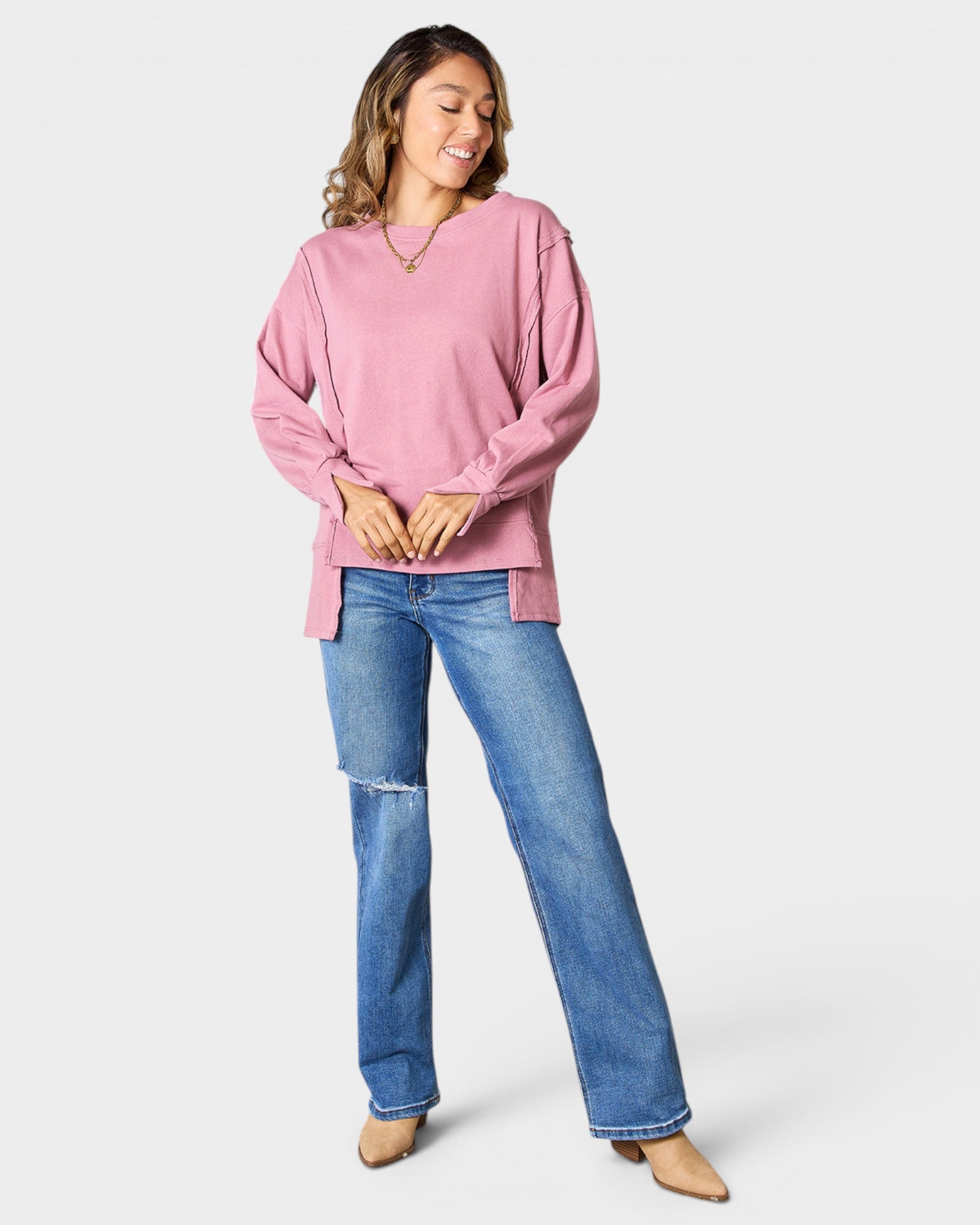 Woman wearing a pink sweater and blue jeans on a white background
