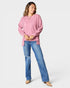 Woman wearing a pink sweater and blue jeans on a white background