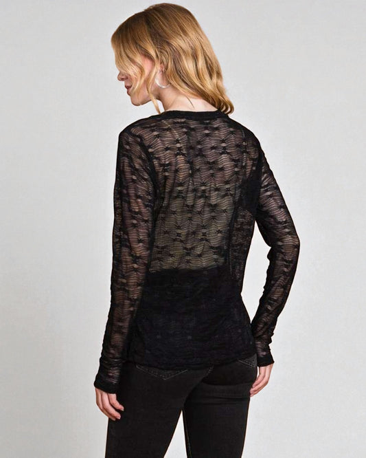 Person wearing a sheer black long-sleeve top against a plain background