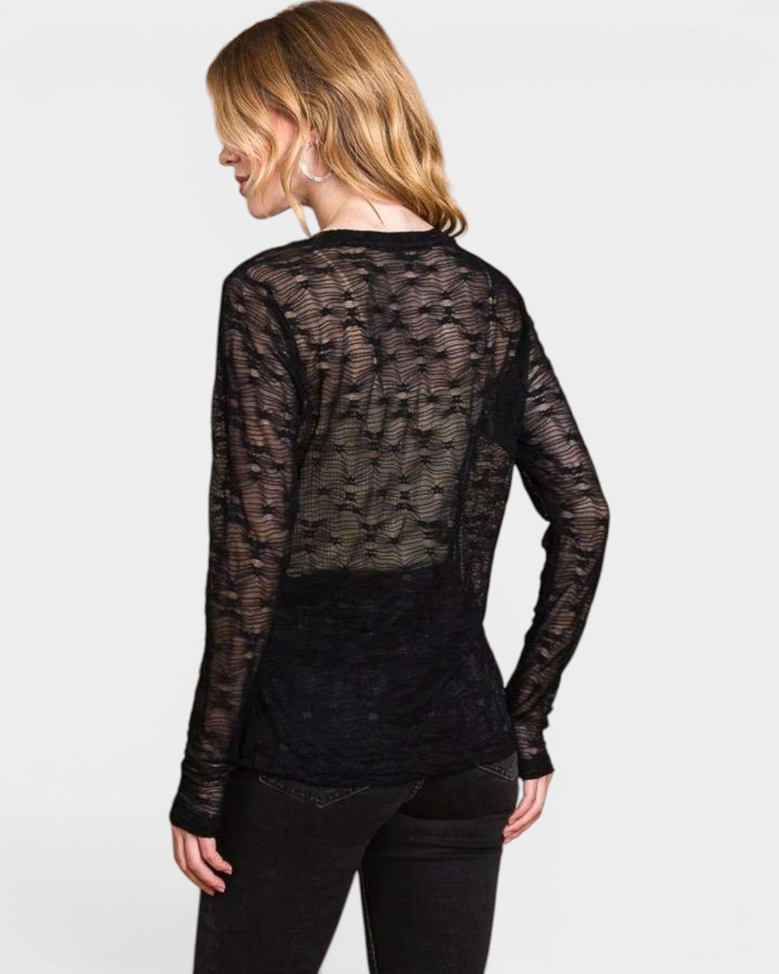 Woman wearing a sheer black long-sleeve top on a white background