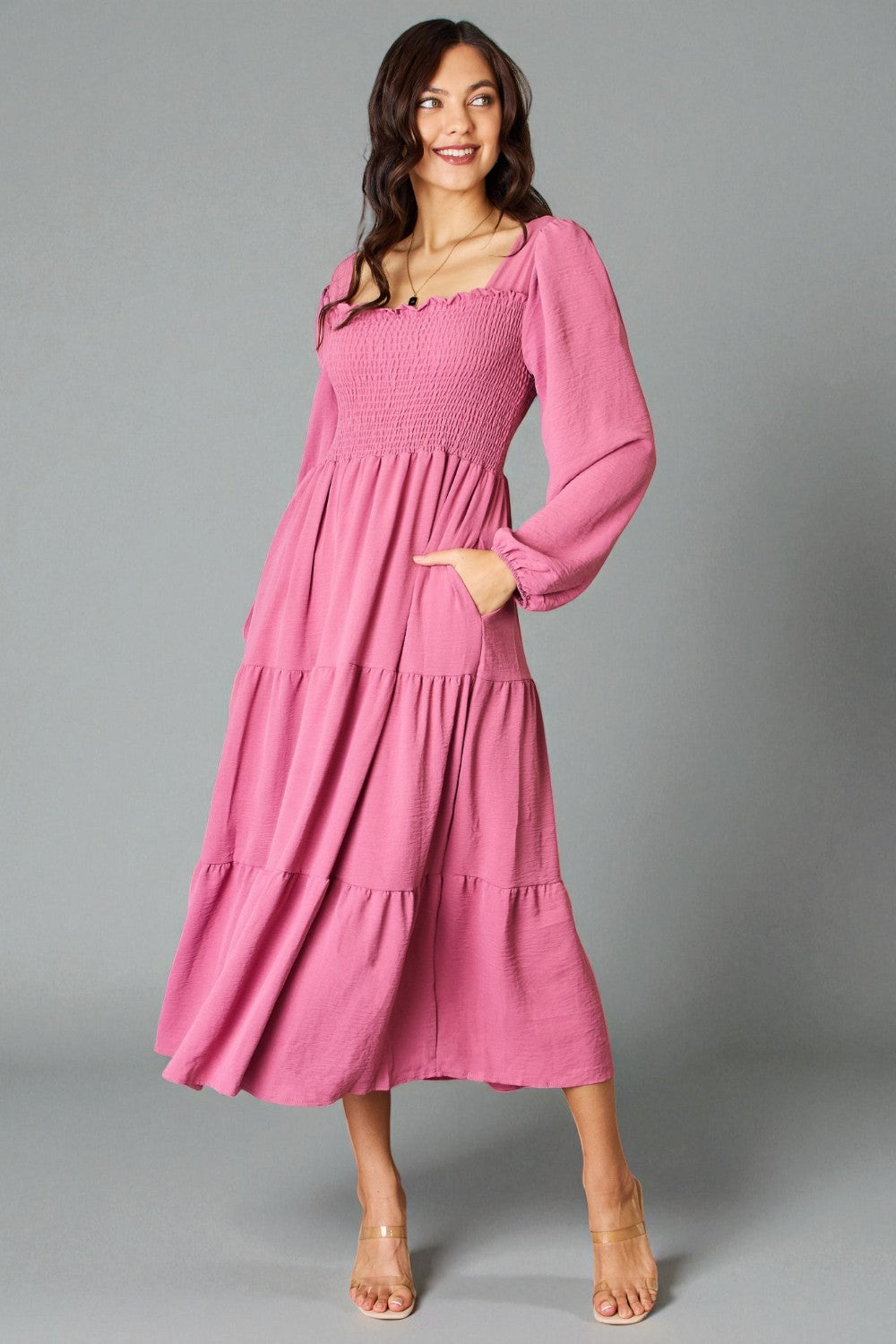 Woman wearing a pink dress against a gray background