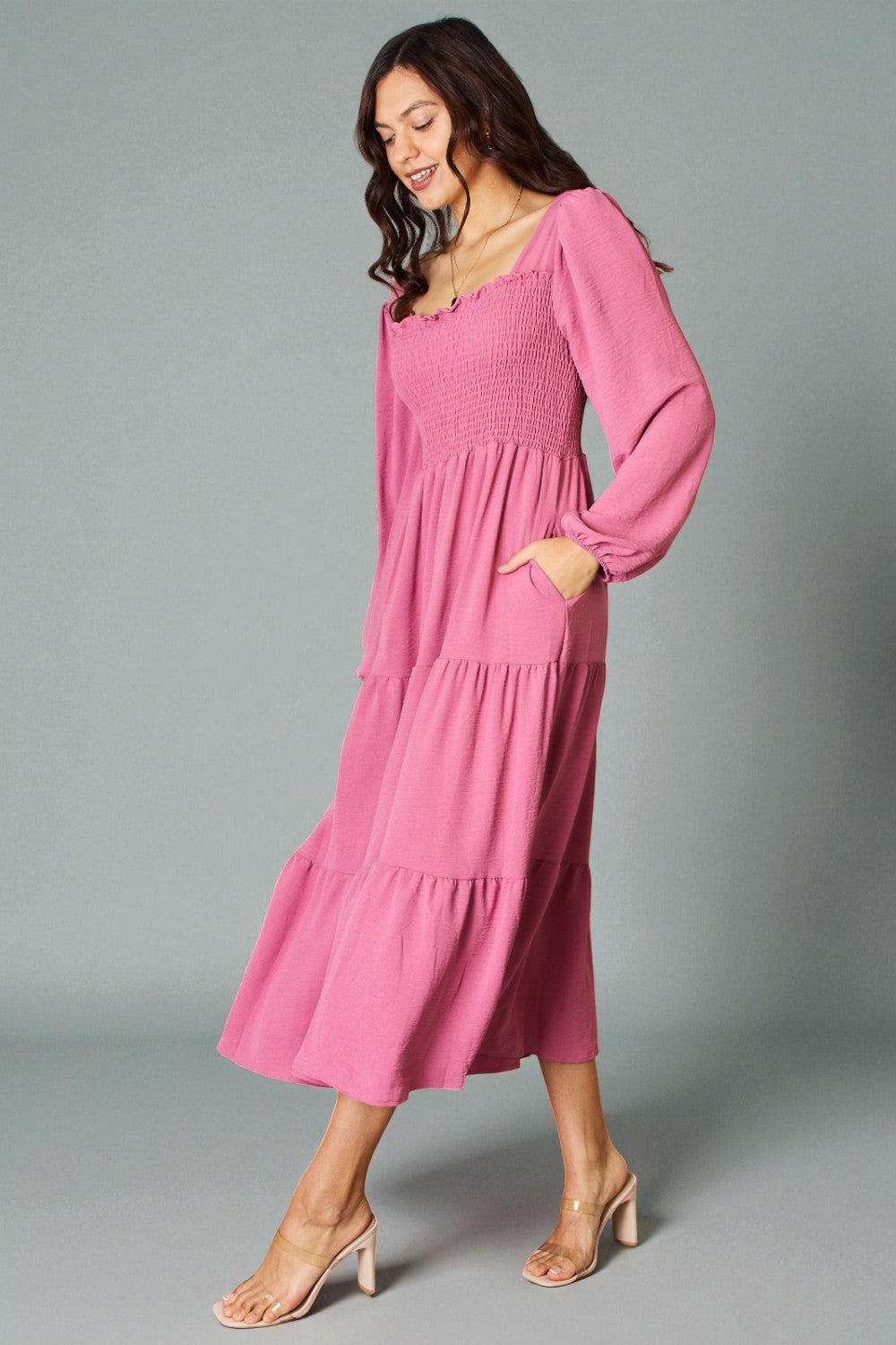 Woman wearing a pink dress against a gray background