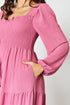 Pink smocked dress with long sleeves on a plain background