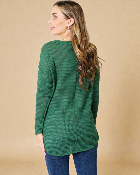 Woman wearing a green textured sweater against a beige background
