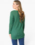 A woman shown from the back wearing a green waffle-knit long-sleeve top and blue jeans against a plain white background.