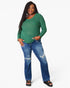 A woman modeling a green long-sleeve waffle-knit top and distressed blue jeans against a plain white studio background.