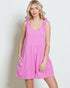 Woman wearing a pink dress with ruffled sleeves against a plain background