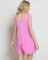Woman wearing a pink romper against a plain background