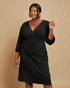 Woman wearing a black dress against a beige background