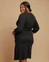 Woman wearing a black ribbed dress against a beige background