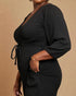 Woman wearing a black ribbed dress against a beige background
