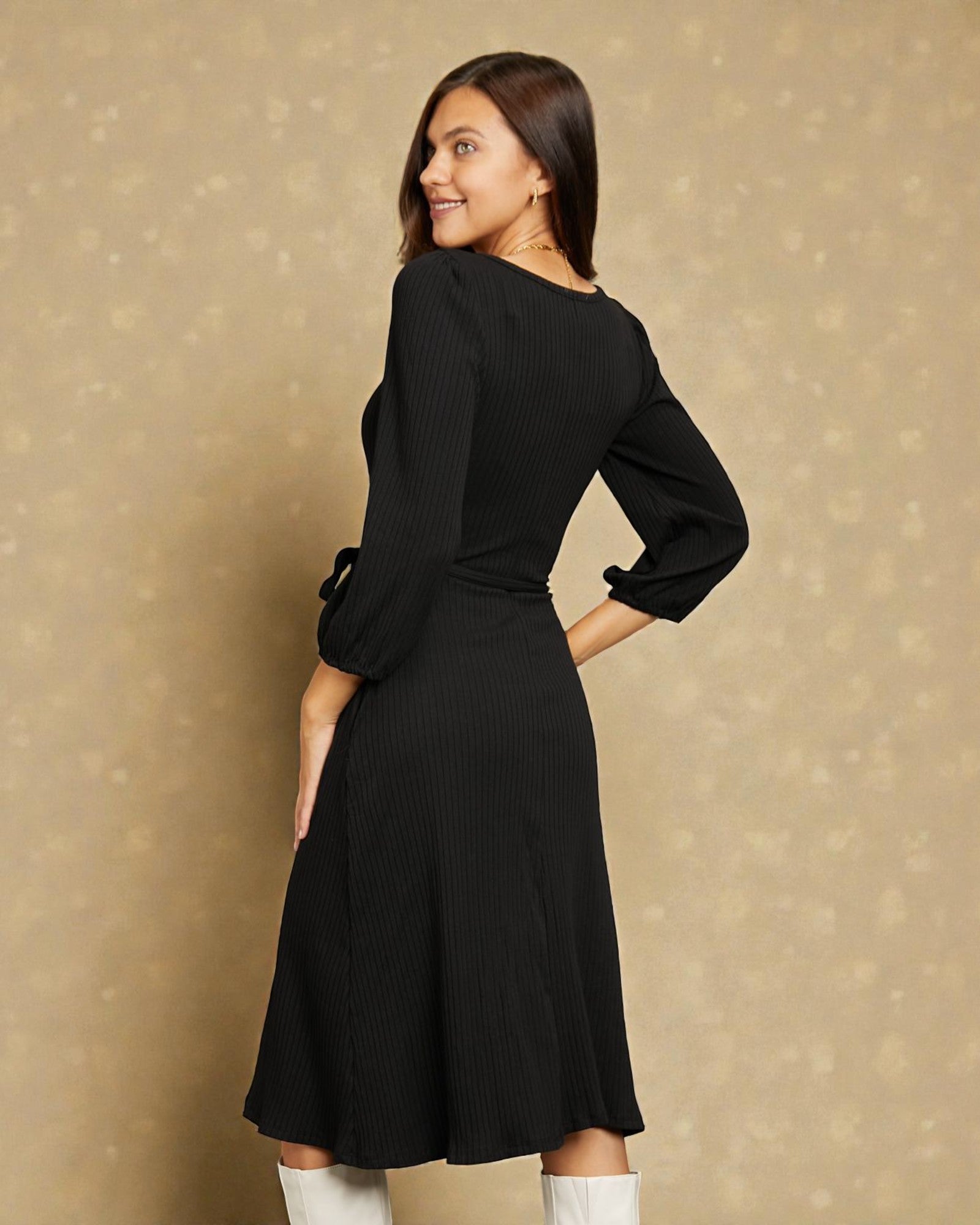 Woman wearing a black dress with long sleeves against a beige background