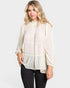 Woman wearing a white blouse with long sleeves on a plain background
