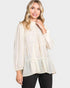 Woman wearing a cream polka dot blouse against a white background
