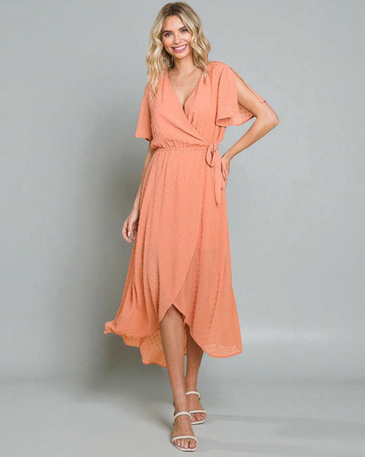 Woman wearing a peach-colored dress against a plain background