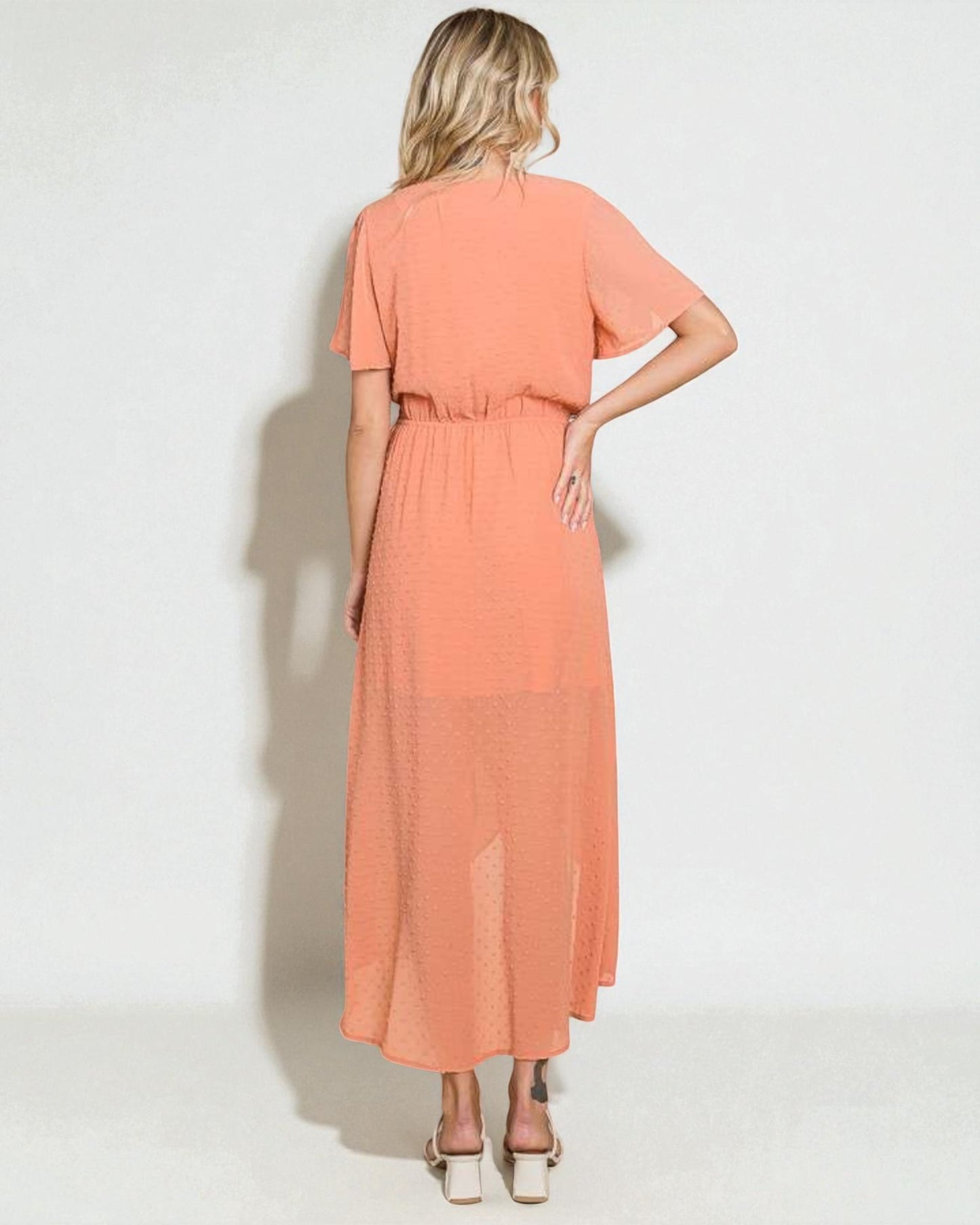 Woman wearing a peach-colored dress on a white background