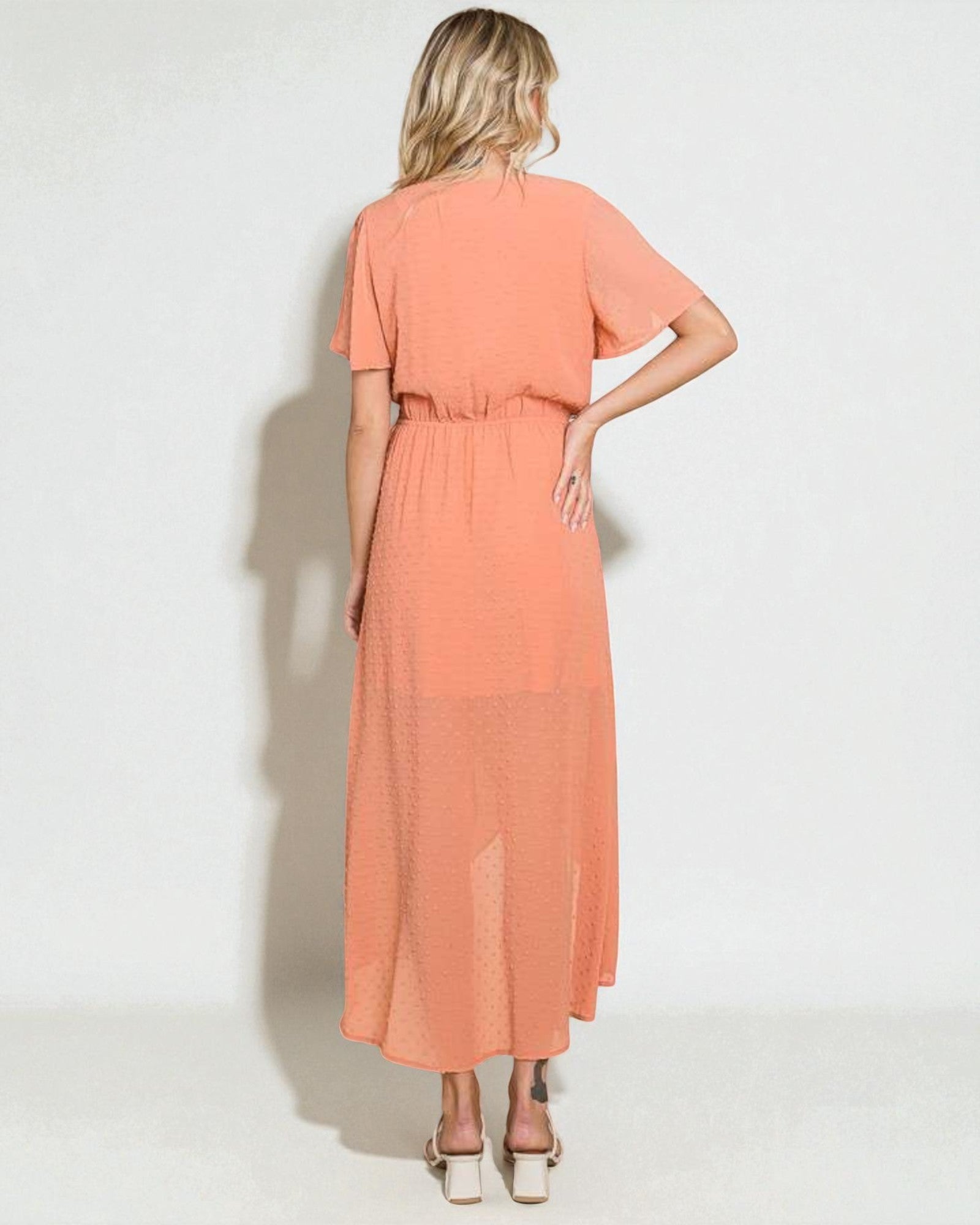 Woman wearing a peach-colored dress on a white background