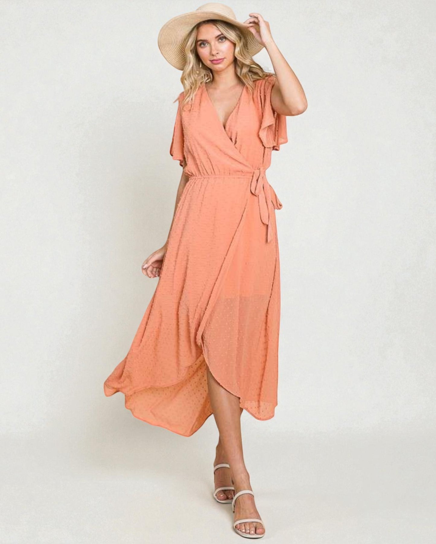 Woman wearing a peach dress and hat on a white background