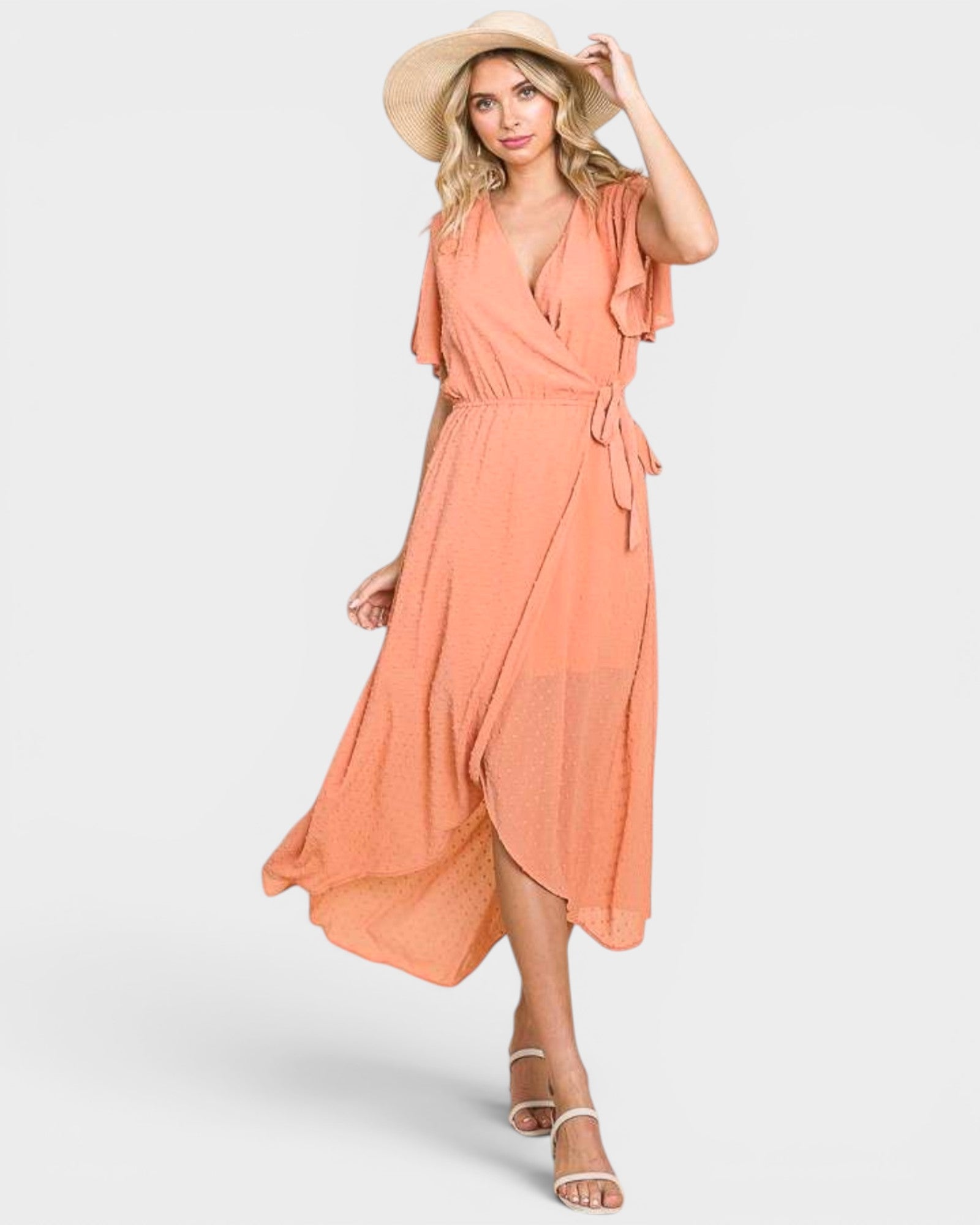 Woman wearing a peach-colored dress and hat on a white background