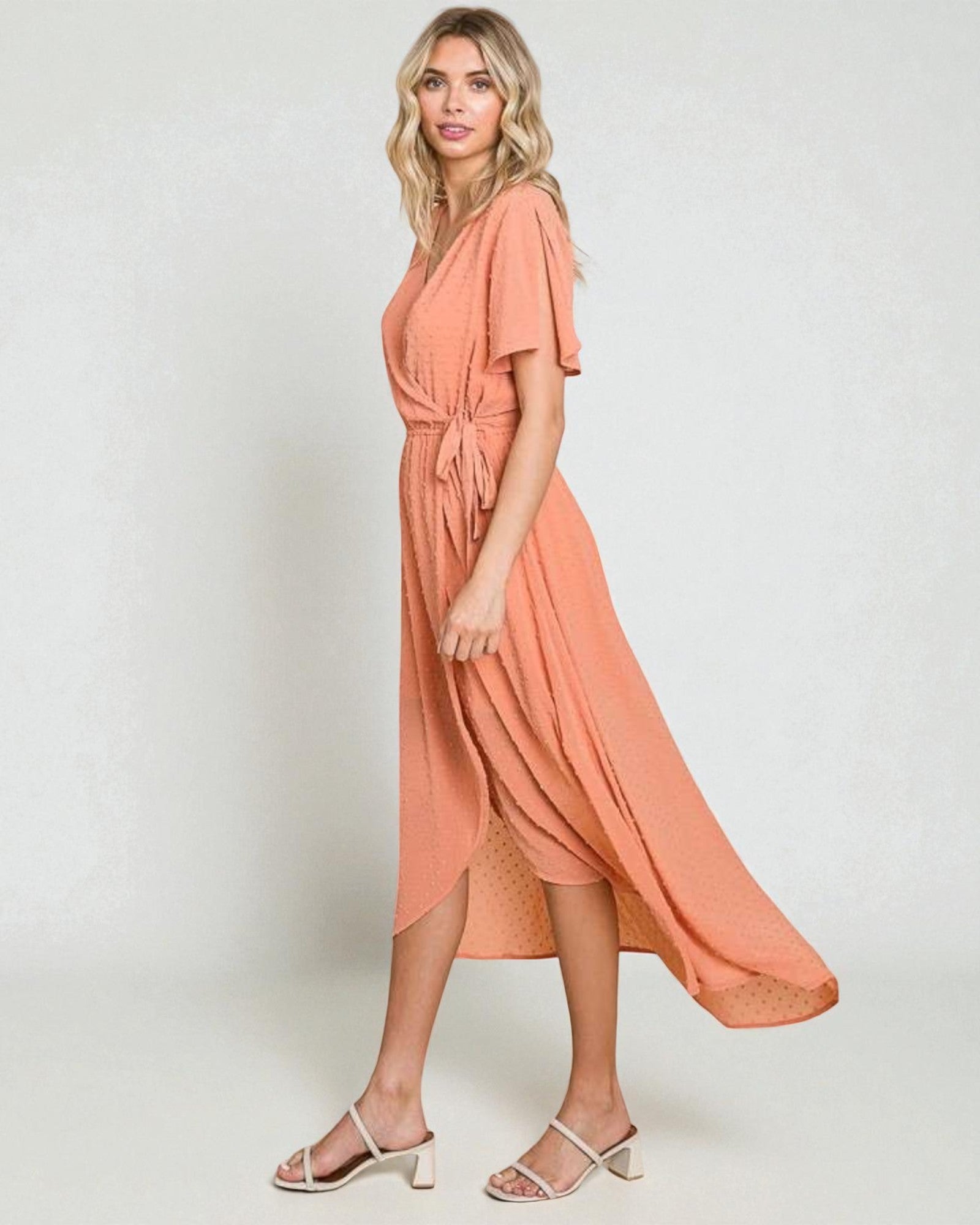 Woman wearing a peach-colored dress on a white background