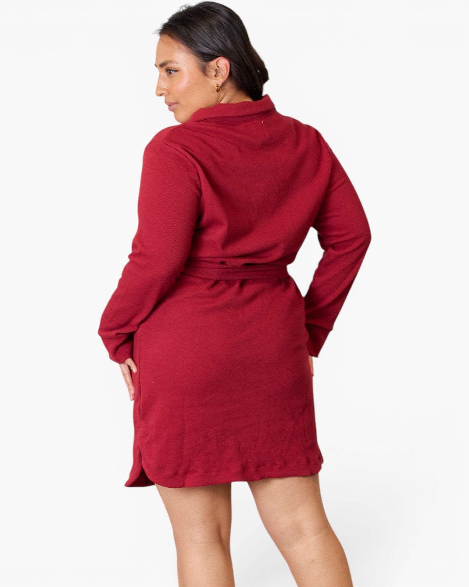 A woman wearing a long-sleeve red wrap-style dress or robe, shown from the back against a plain light background.