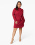A woman modeling a long-sleeve red mini dress with a collar, chest pocket, and matching waist tie, photographed against a clean light gray studio background.
