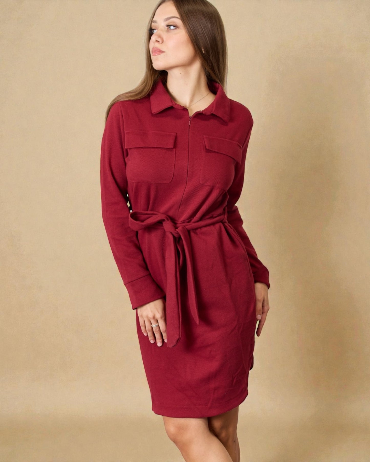 Woman wearing a red dress with a belt against a beige background