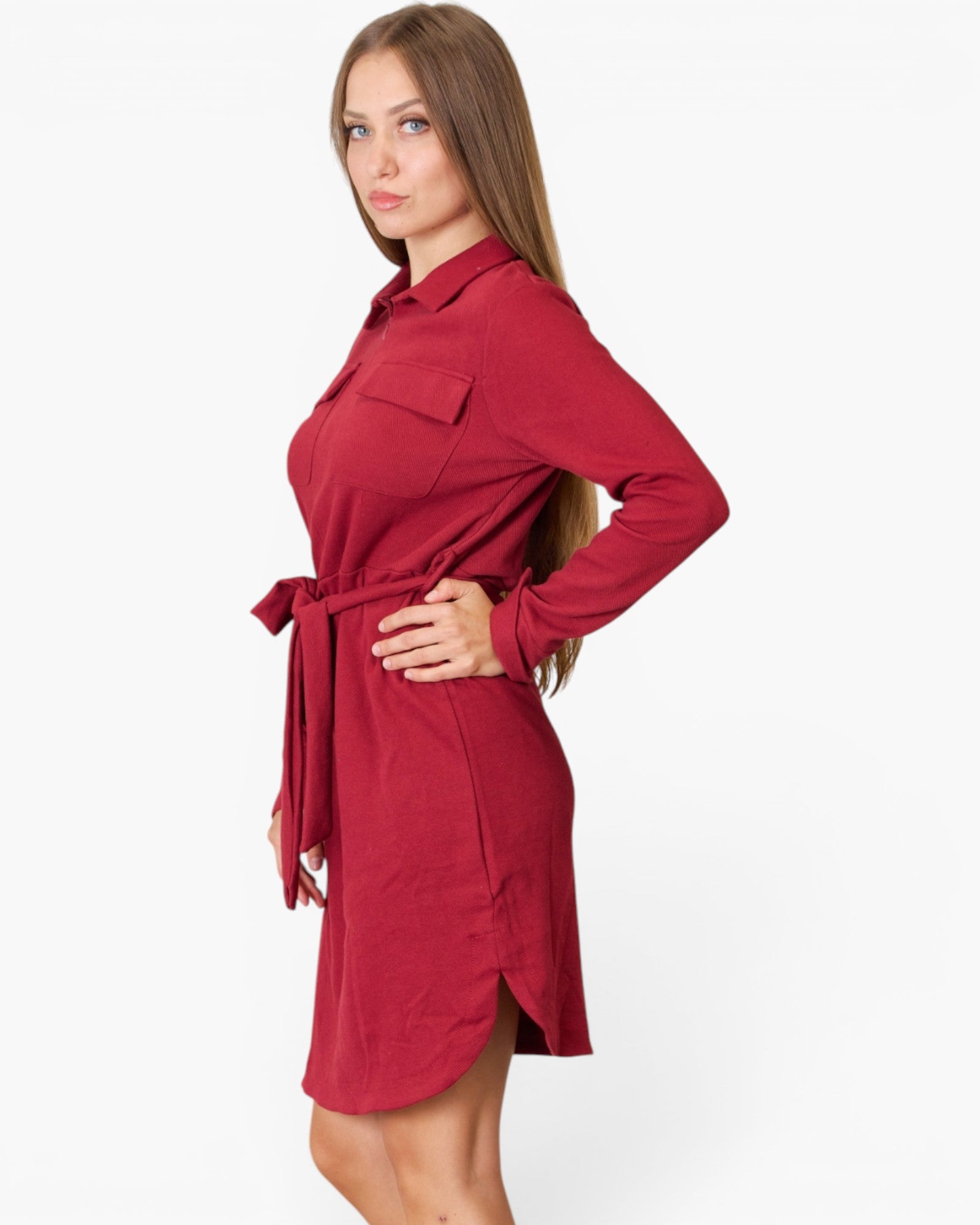 A woman modeling a long-sleeve red shirt dress with a tie waist belt, shown from a side profile against a plain white background.