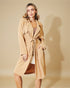 Woman wearing a beige trench coat against a beige background