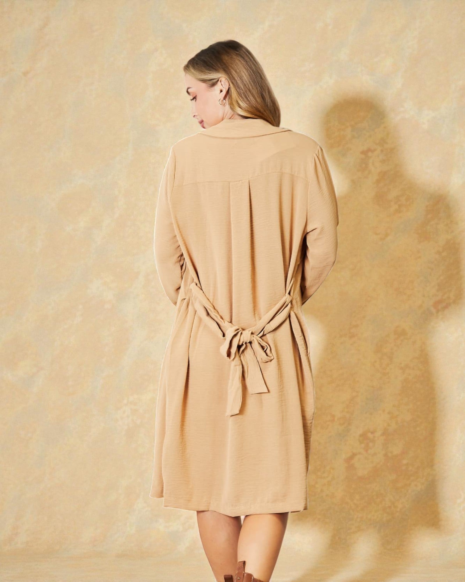 Woman wearing a beige dress against a textured beige background