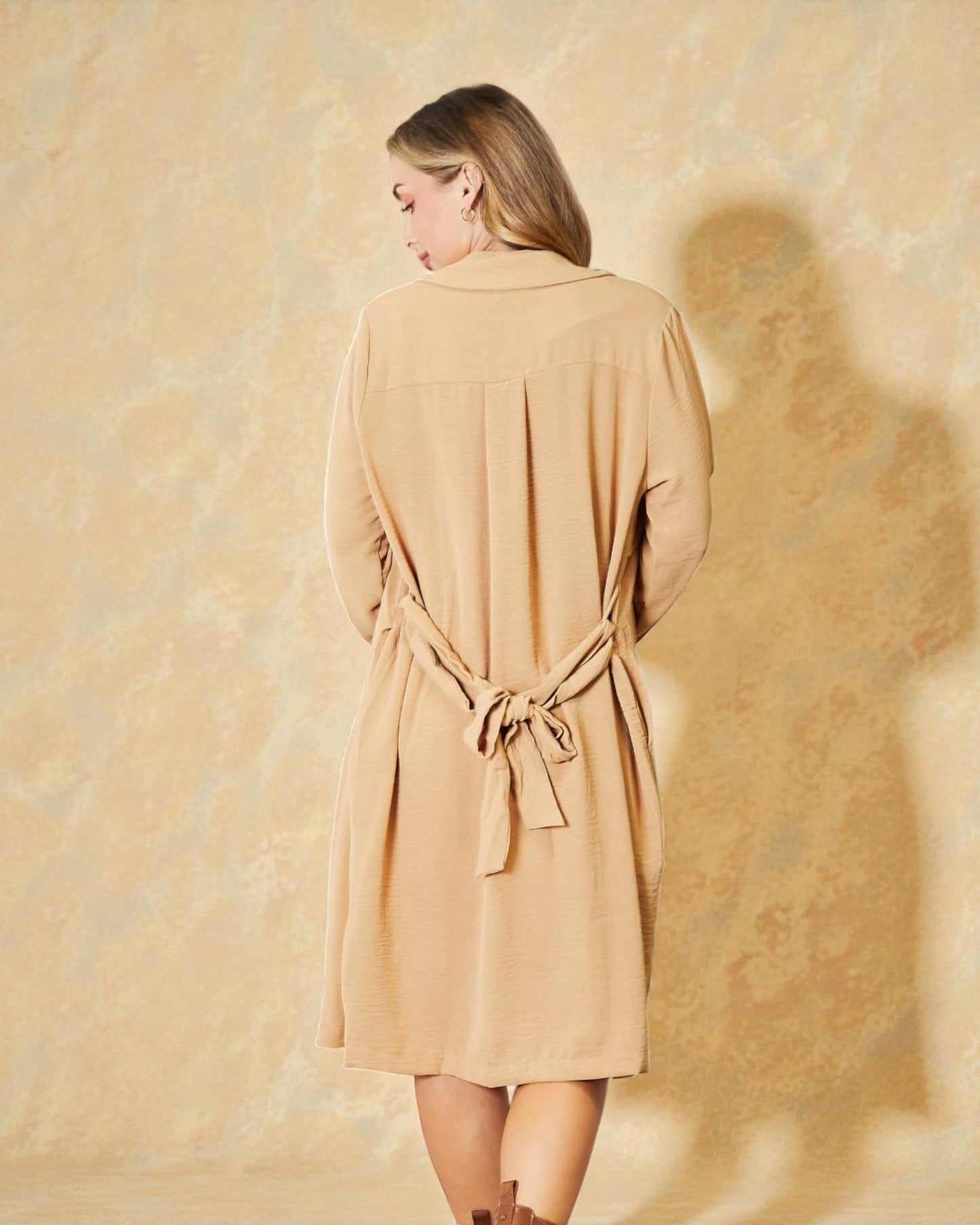 Woman wearing a beige dress against a textured beige background