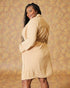 Woman wearing a beige dress against a patterned background