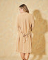 Woman wearing a beige dress against a textured beige background